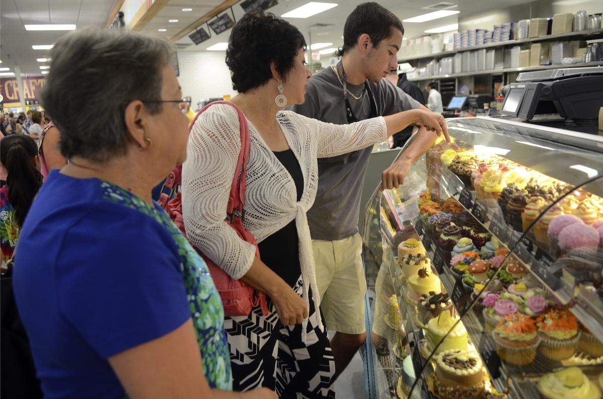 From left, Marge Chavis of Lumberton, N.C., and Belinda Listoe and her son Christian, both of Fayetteville, N.C., select cupcakes July 30, 2014, at the Whole Foods Market's bakery counter during the store's grand opening on Hilton Head Island. The store closed 10 years later in 2024.