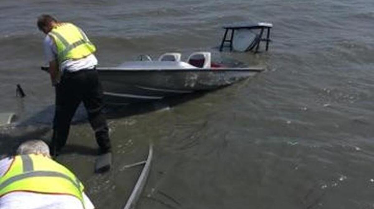 Responders pull the boat to shore to drain it after boaters were rescued.