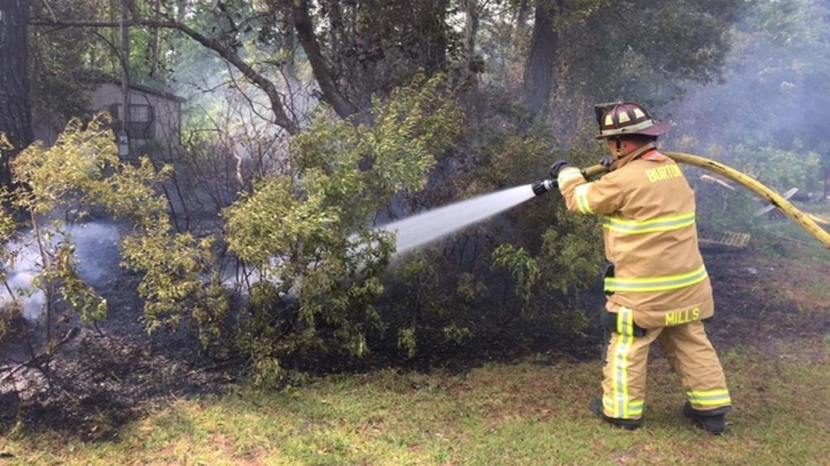 A Burton Fire District firefighter puts out a Capehart Cirlce brush fire Thursday evening that was endangering nearby property.