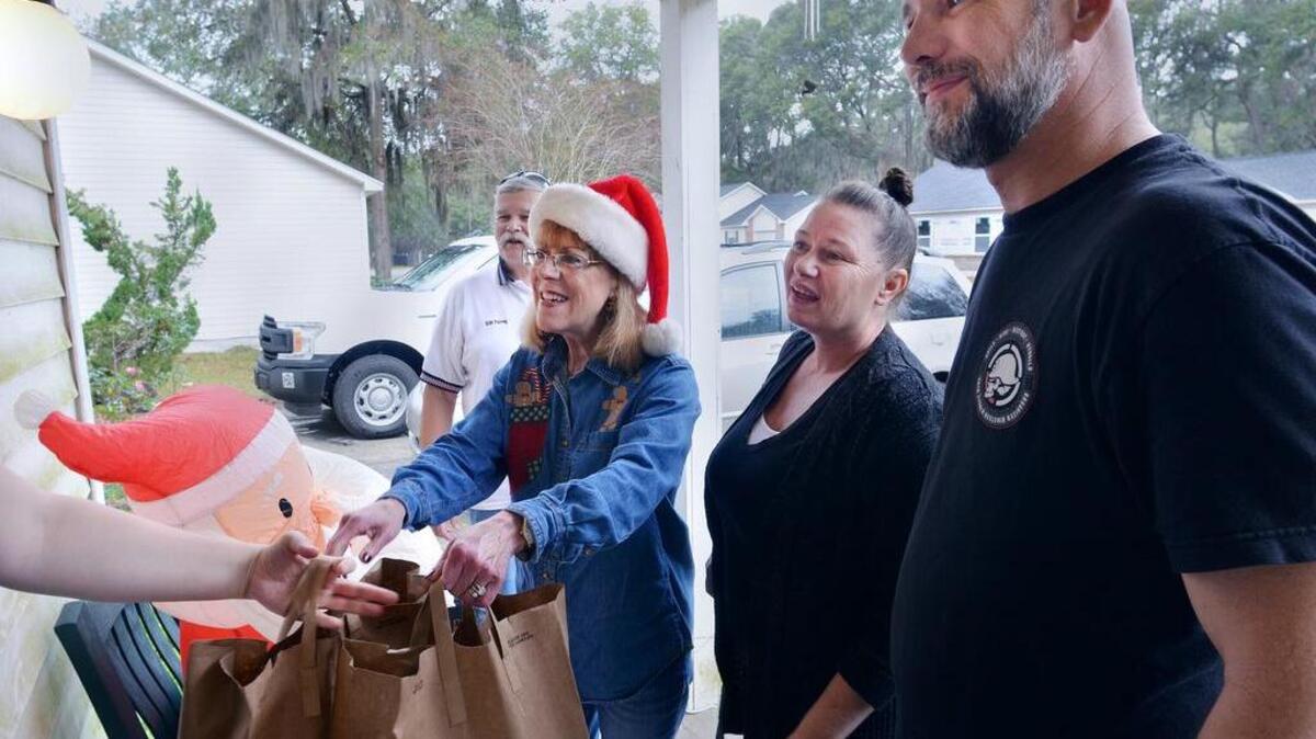 From left, Bill Perry, Donna Berger, and Shani and Troy Zimmerman, all volunteers with the Beaufort Car and Truck Club, drop off Christmas meals to a recipient on Lady's Island during the Christmas meals on Classic Wheels food distribution effort on Sunday. The 14th annual event provided 250 boxed Christmas dinners to less fortunate families in northern Beaufort County.