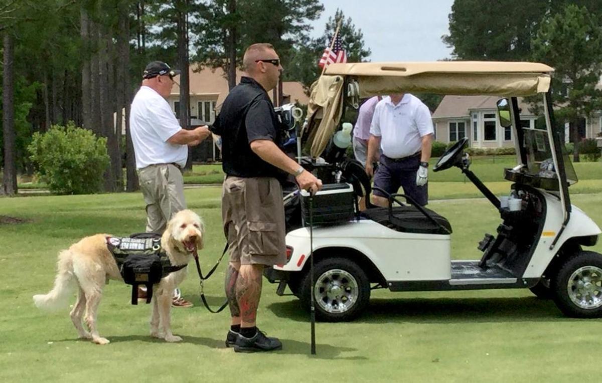 Justin Madore and his service dog, Cody, stand in the fairway at Hampton Hall Golf Club on Monday, May 16, 2016, during the Wounded Heroes Golf Classic charity event.