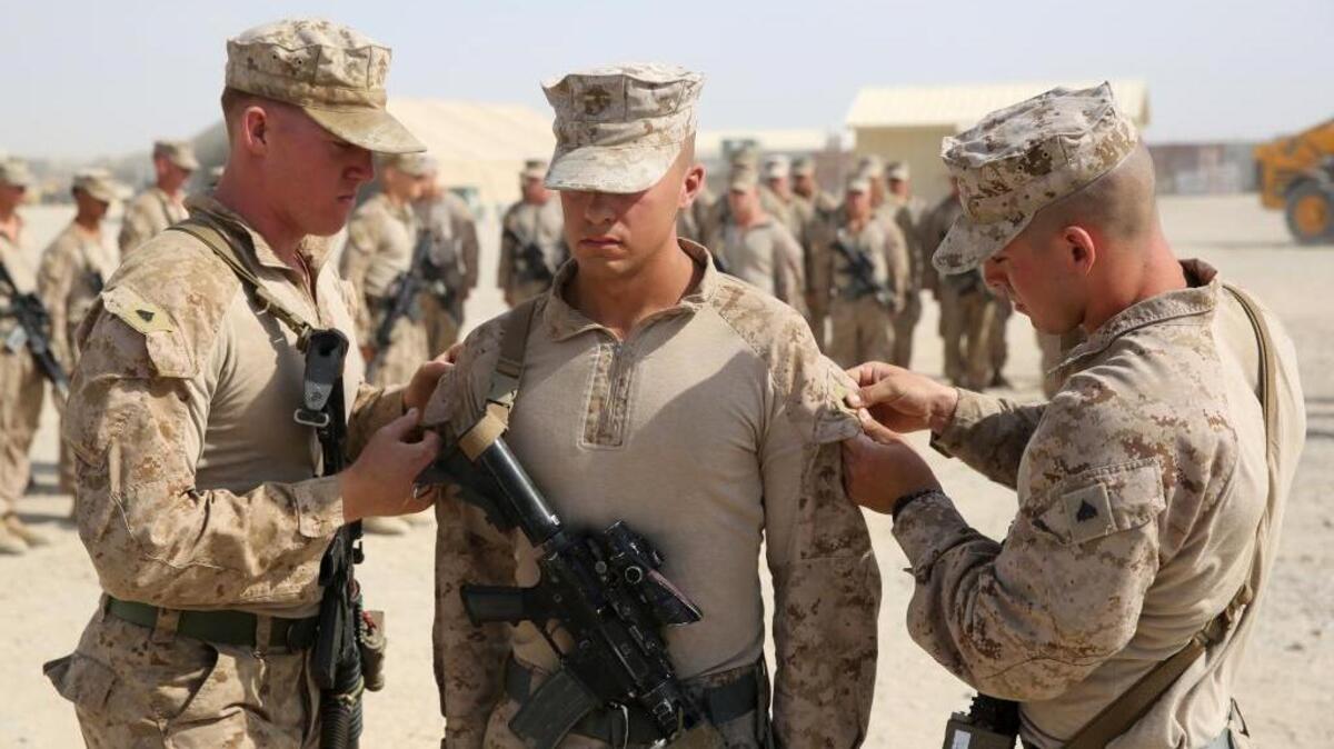 Marines pin new rank insignia on a recently promoted comrade in 2014, in Afghanistan.