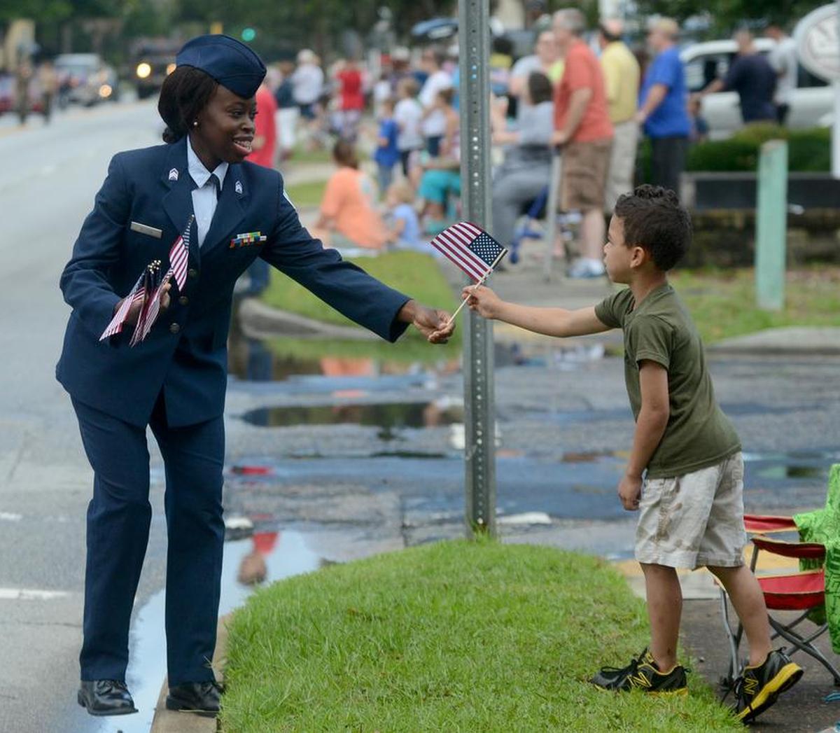 A woman walking with the American Legion float gives an American flag to a child during the Memorial Day Parade along Boundary Street on Monday, May 30, 2016, in Beaufort.