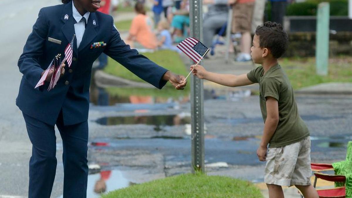A woman walking with the American Legion float gives an American flag to a child during the Memorial Day Parade along Boundary Street on Monday, May 30, 2016, in Beaufort.