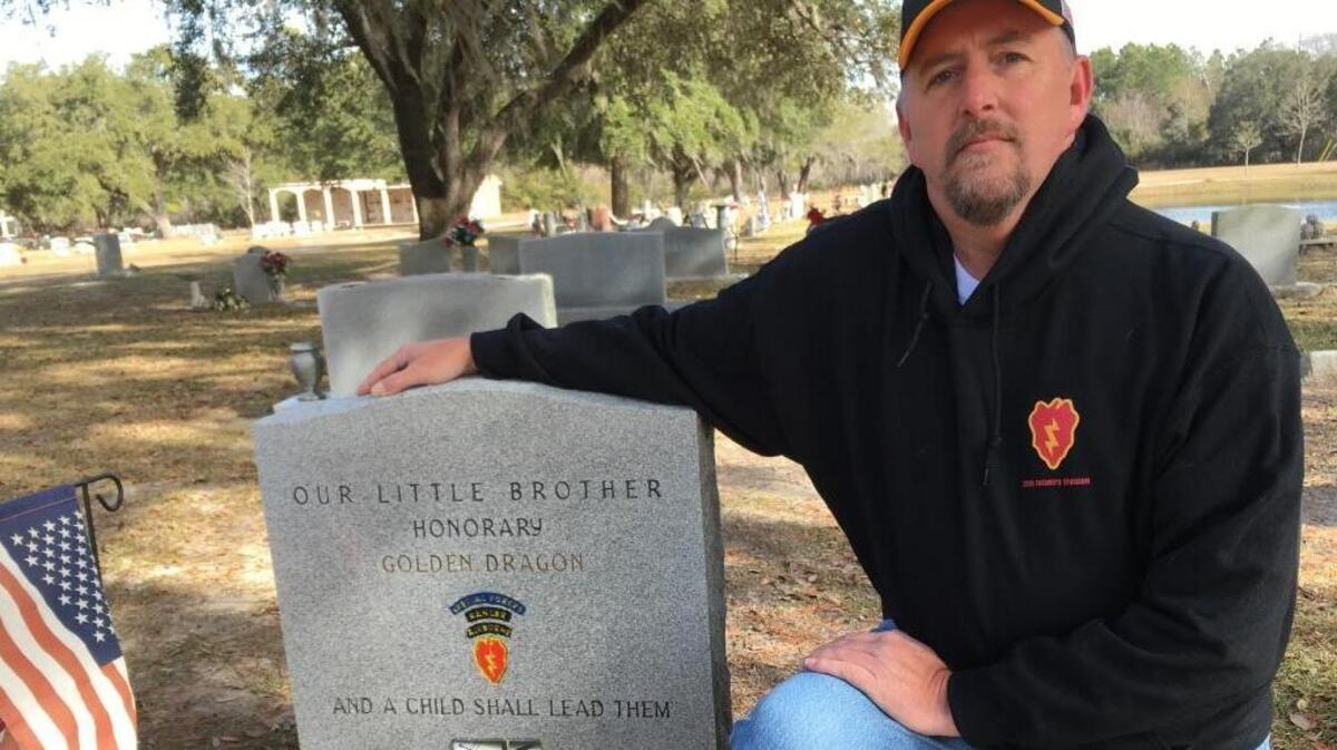 James McDiffett Sr. kneels at the grave of his son, James McDiffett Jr., on Tuesday. In December, someone apparently stole a bench the father made to remember the 6-year-old who died in 2014.