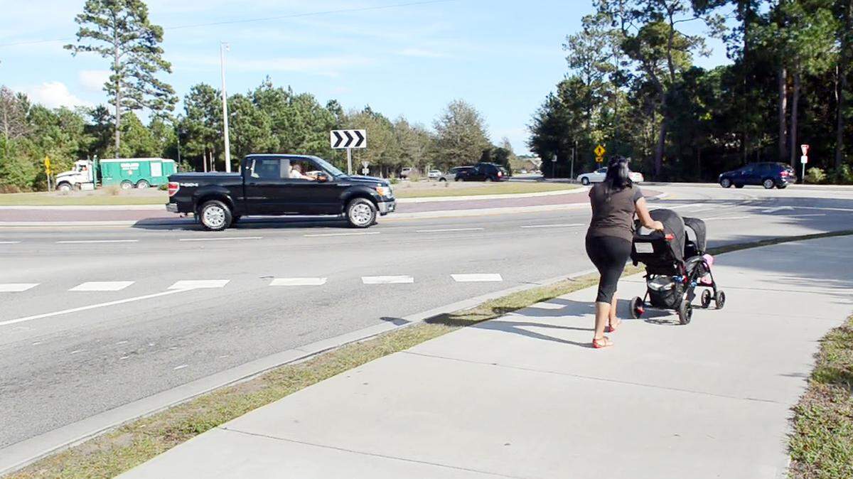 A woman pushes a baby carriage around the Bluffton Road roundabout at Bluffton Parkway on Oct. 31, 2013, as traffic swirls past. Blufftonians are circulating an online petition asking the SC Department of Transportation to lower the speed limit at the roundabout. Leah McCarthy, who started the petition, had a minor wreck there in July.