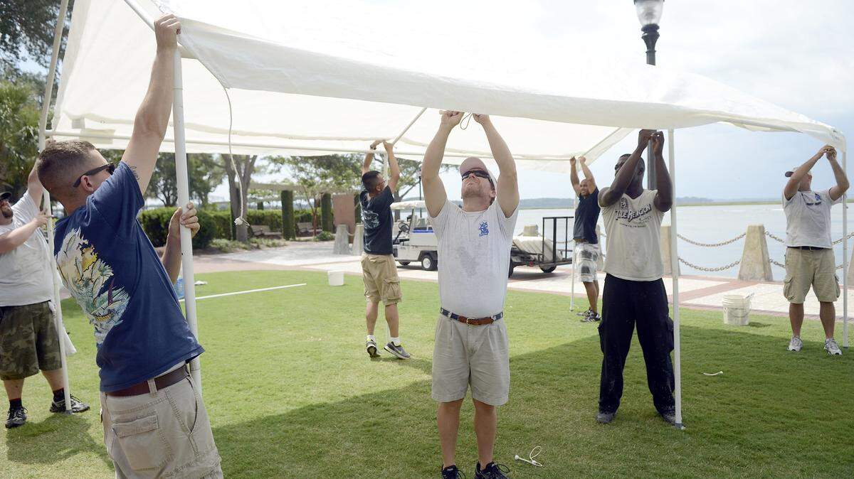 Chris Canaday, center, sports coordinator and public relations for the 59th Annual Water Festival, secures a tarp to the tent frame July 17, 2014, with help from other volunteers at Henry C. Chambers Waterfront Park in Beaufort. The shelter will be used to sell festival T shirts.