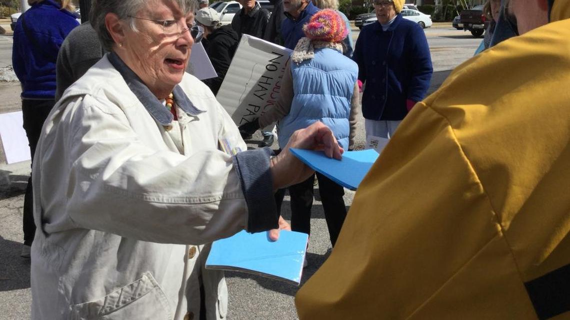 Alison Davidow, with Beaufort Indivisible, passes out index cards to protesters at Boundary Street and Ribaut Road on Tuesday. A group of about 75 met to oppose Sheriff P.J. Tanner’s plan to use a team of deputies to enforce federal immigration laws.