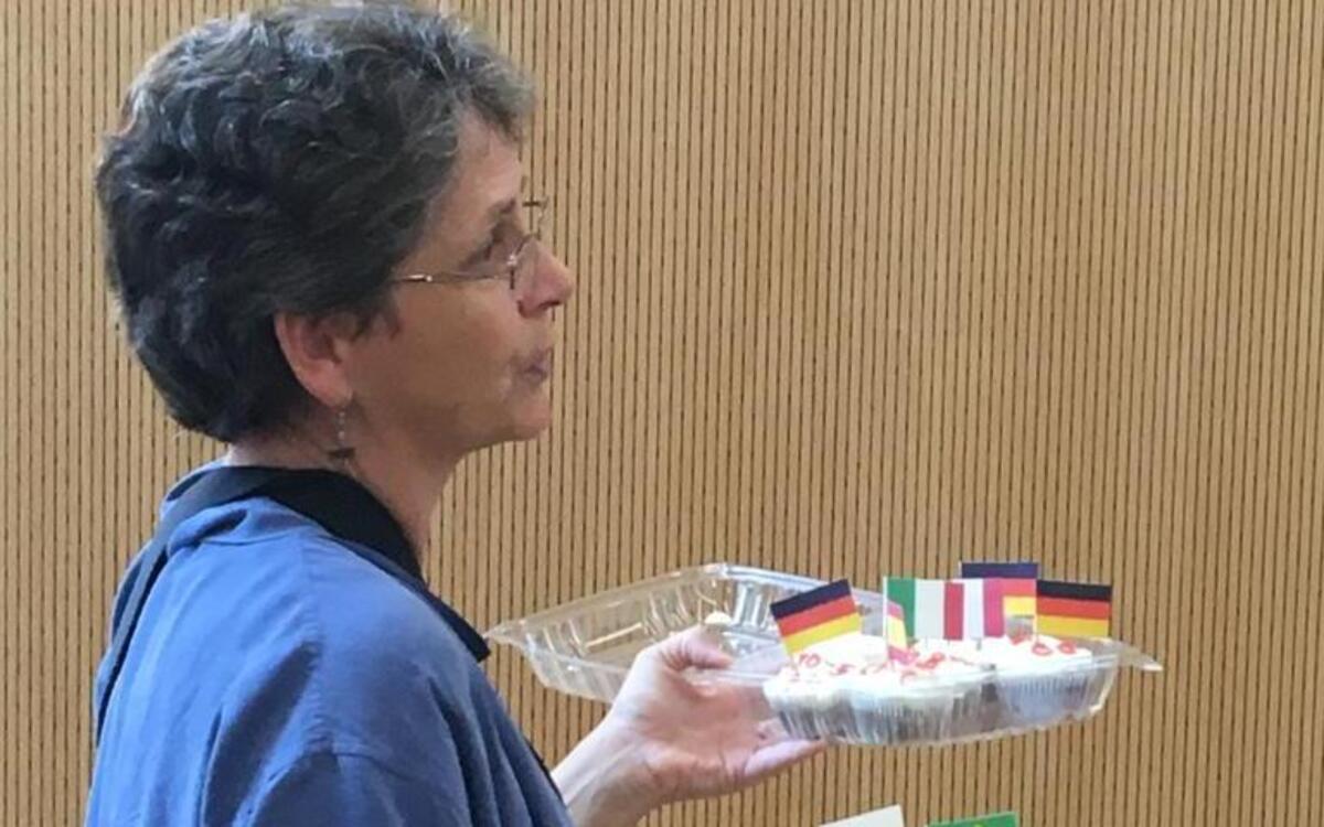 Local FLAG coordinator Connie Polk holds cupcakes with flags representing the homelands of a group of exchange students.