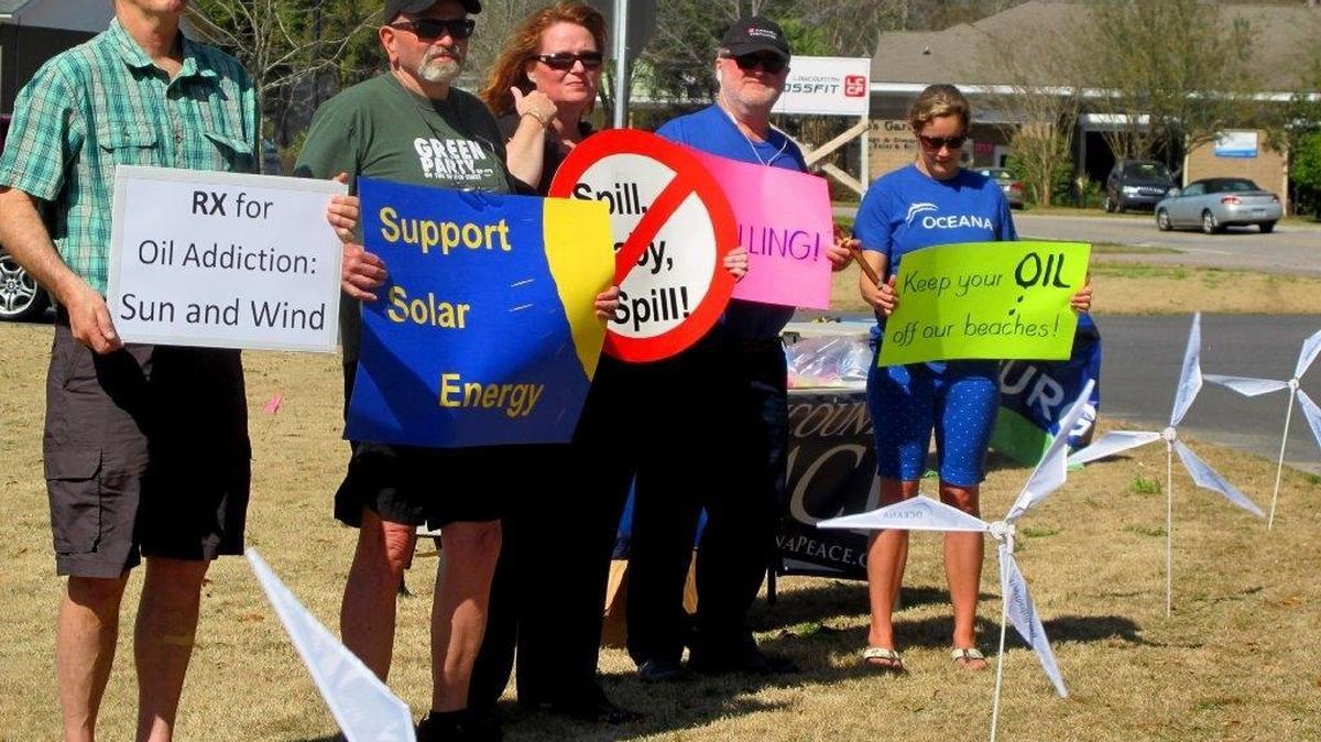 File: Opponents of opening waters off the Carolinas coast to exploration for oil and natural gas hold signs on March 11, 2015 in Mount Pleasant, S.C. They were standing outside a motel where the federal Bureau of Ocean Energy Management held a meeting to take public comment on opening areas to drilling.