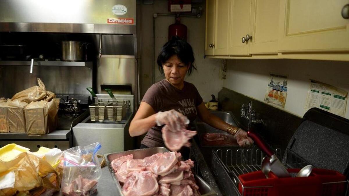 Rita Wolfe, who owns the Fillin' Station with her husband Mark, prepares pork chops for the Thursday night fried pork chop dinner.