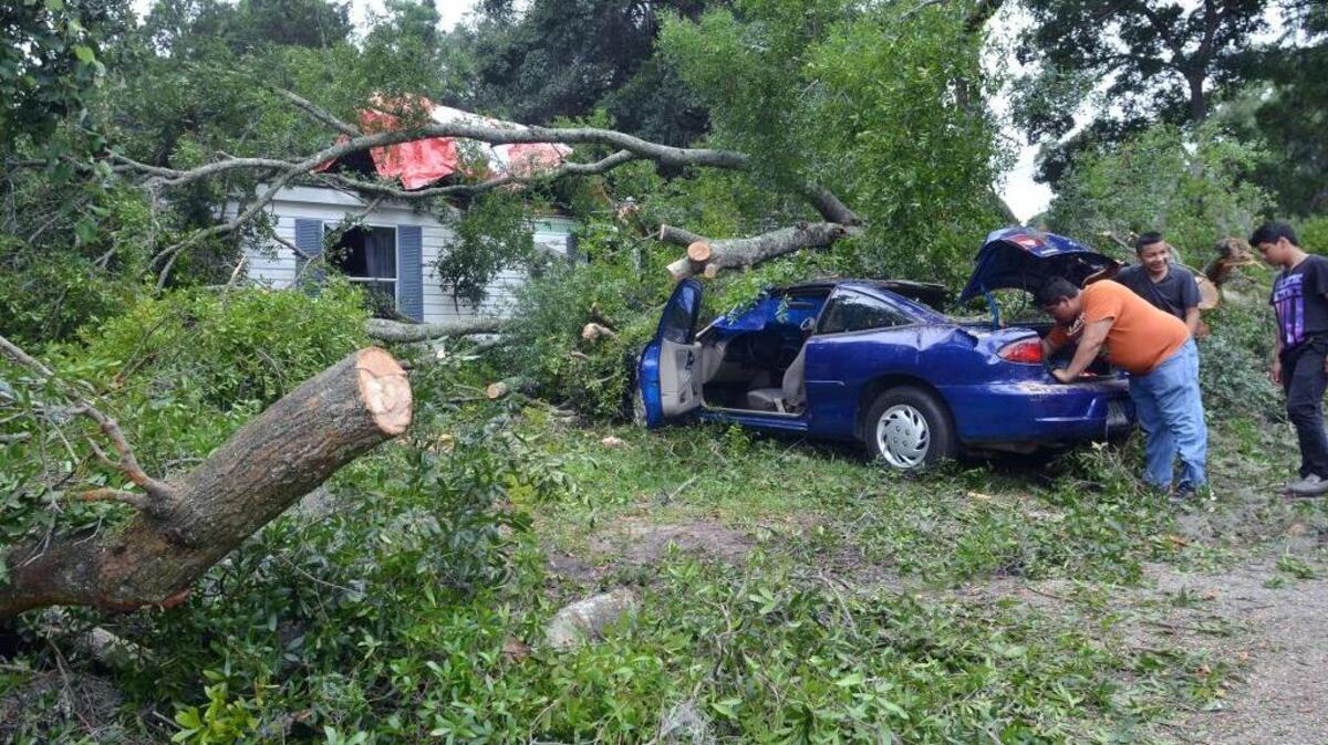 On Saturday, residents and friends of a Beaufort mobile home on Tekoa Lane that was hit by a falling tree during Friday's violent thunderstorms salvage what they can from one of two cars that were also hit by the tree. Jose Gonzalez, one of the home's six residents, said he was planning on staying with a relative in Beaufort.