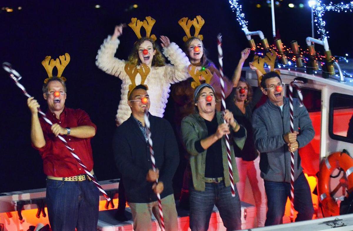 Passengers aboard Orion, captained by Gene Clark, wave candy canes and dance as they pass the the reviewing stand at Henry C. Chambers Waterfont Park on Saturday. The boat's theme was “Rudolph the Red Nosed Reindeer.”