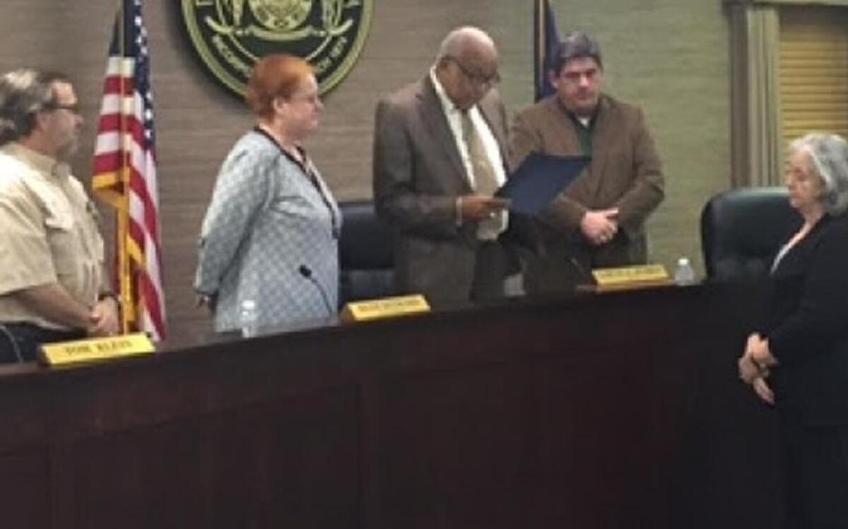 Port Royal Mayor Sam Murray reads a resolution recognizing longtime town clerk Tanya Payne, right, as she retired last week. Payne started as a utility clerk in 1992.