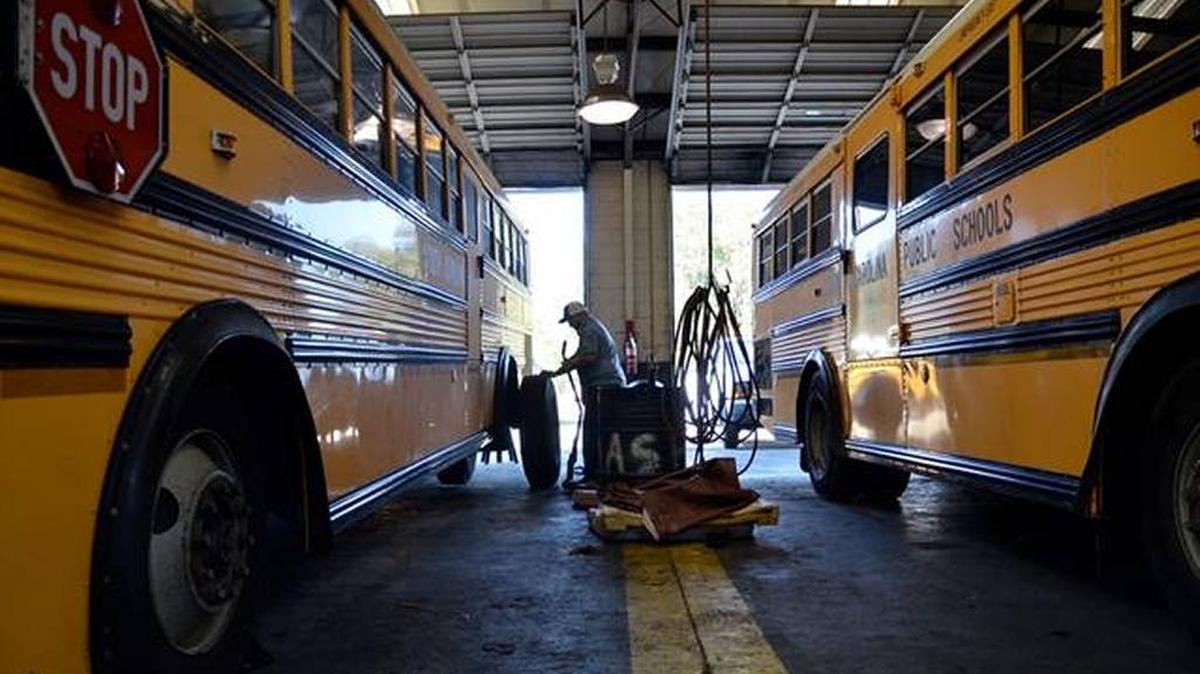 In this file photo, mechanic Eric Albertson, center, removes tires from a school bus during its yearly full maintenance check at the SC School Bus Maintenance Shop in Beaufort.