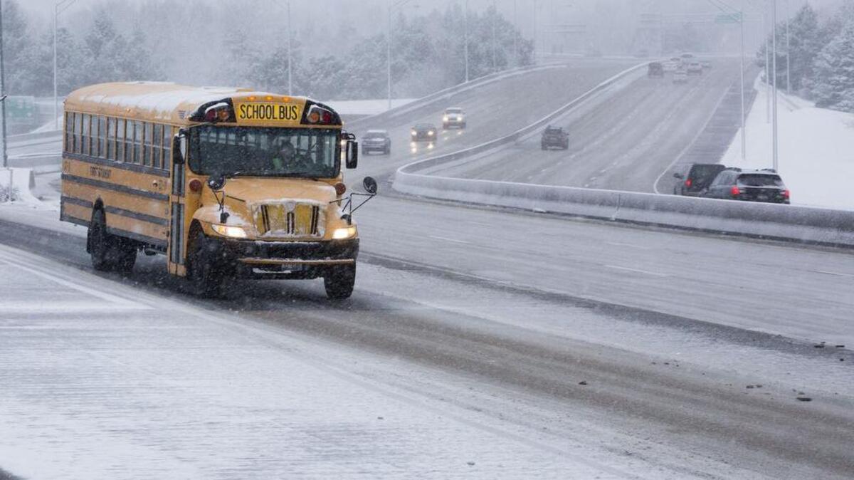 A stock image of a school bus driving through snow.
