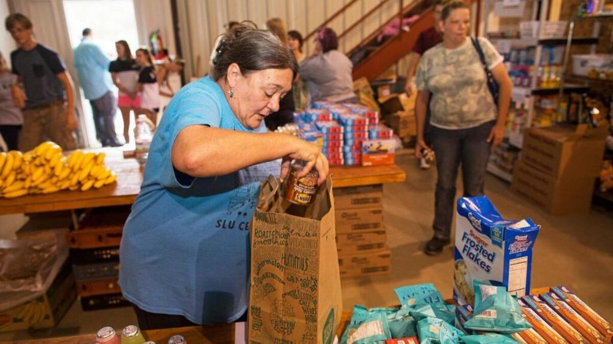 A volunteer in Walker, La., loads a shopping bag full of donated groceries at a church-turned shelter on Sunday, Aug. 21, 2016, for those displaced by last week’s historic flooding.