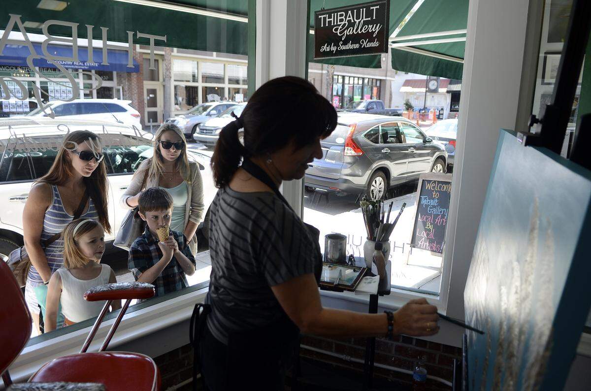 From left, Shanan Hoy, Riley Hoy, Trent Hoy, and Ashtin Ewing, all of Jacksonville, Fla., watch as Mary Thibault paints in the window of the Thibault Gallery on March 21, 2014, on Bay Street in Beaufort.