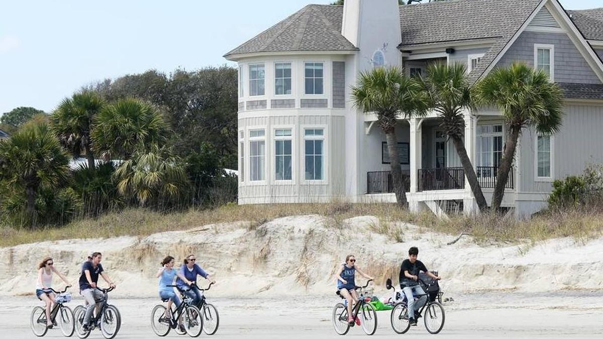 Bicyclists pedal past an eroded stretch of North Forest Beach on April 1, 2015, that has been slated for renourishment in 2016.