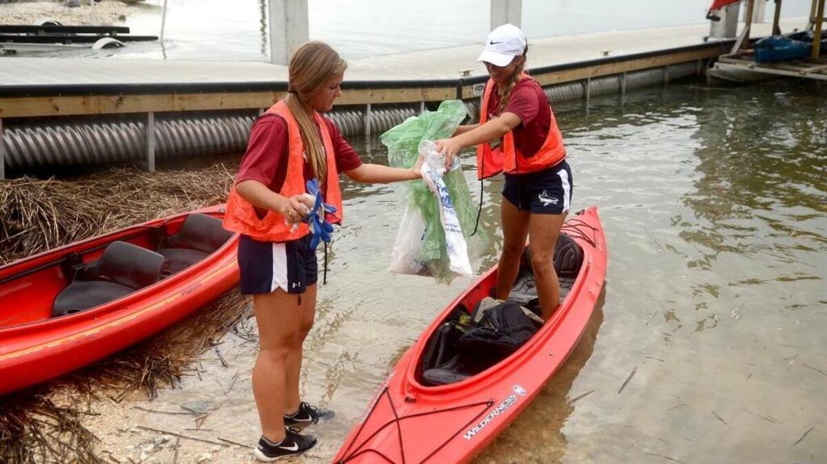 Bailee Barker, right, hands bags of trash to Marissa Becker at the Bluffton Oyster Factory Park on Sept. 17, 2016. They are members of the USCB softball team.