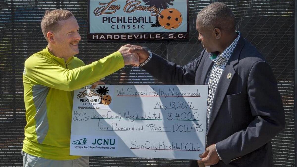 Reuben Oder (left), vice president of the Sun City Pickleball Club, presents a $4,000 check to a representative of Jasper County Neighbors United after the Low Country Pickleball Classic on Sunday, April 17, 2016.