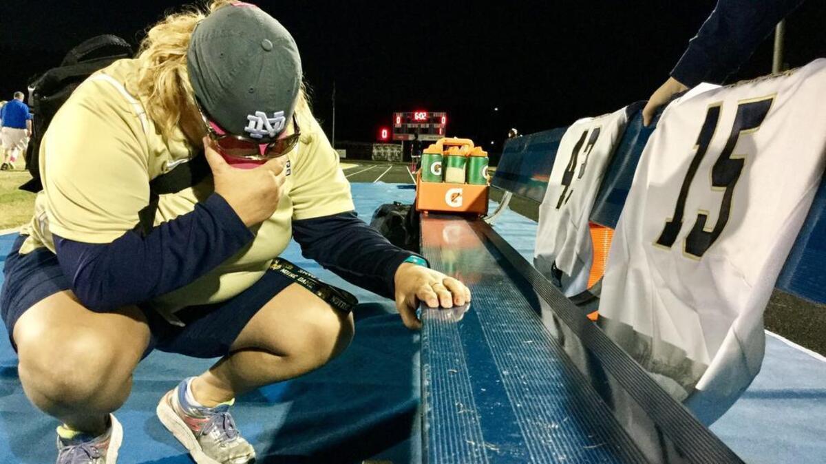 Kim DeReamer, head trainer for the Battery Creek High football team, takes a moment before the game at May River on Oct. 21, 2016, to think about the three players injured in a car accident.