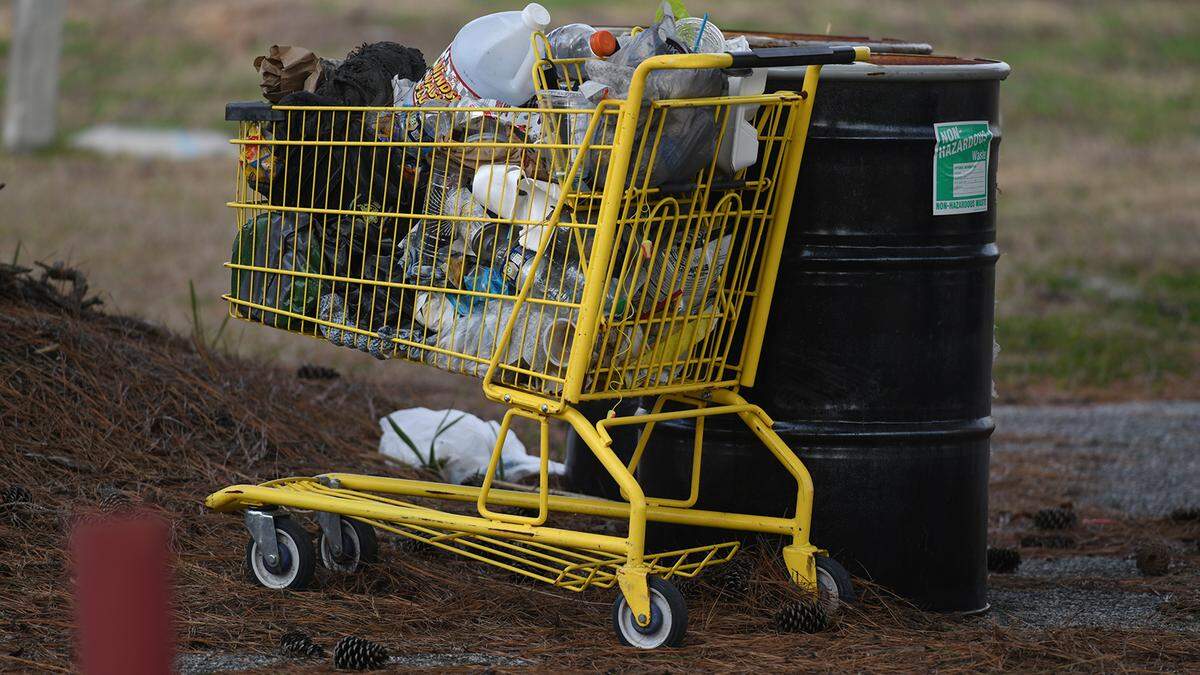 An abandoned shopping cart full of personal items sits in the parking lot of the former gas station at the entrance to the eastbound bridges to Hilton Head Island.