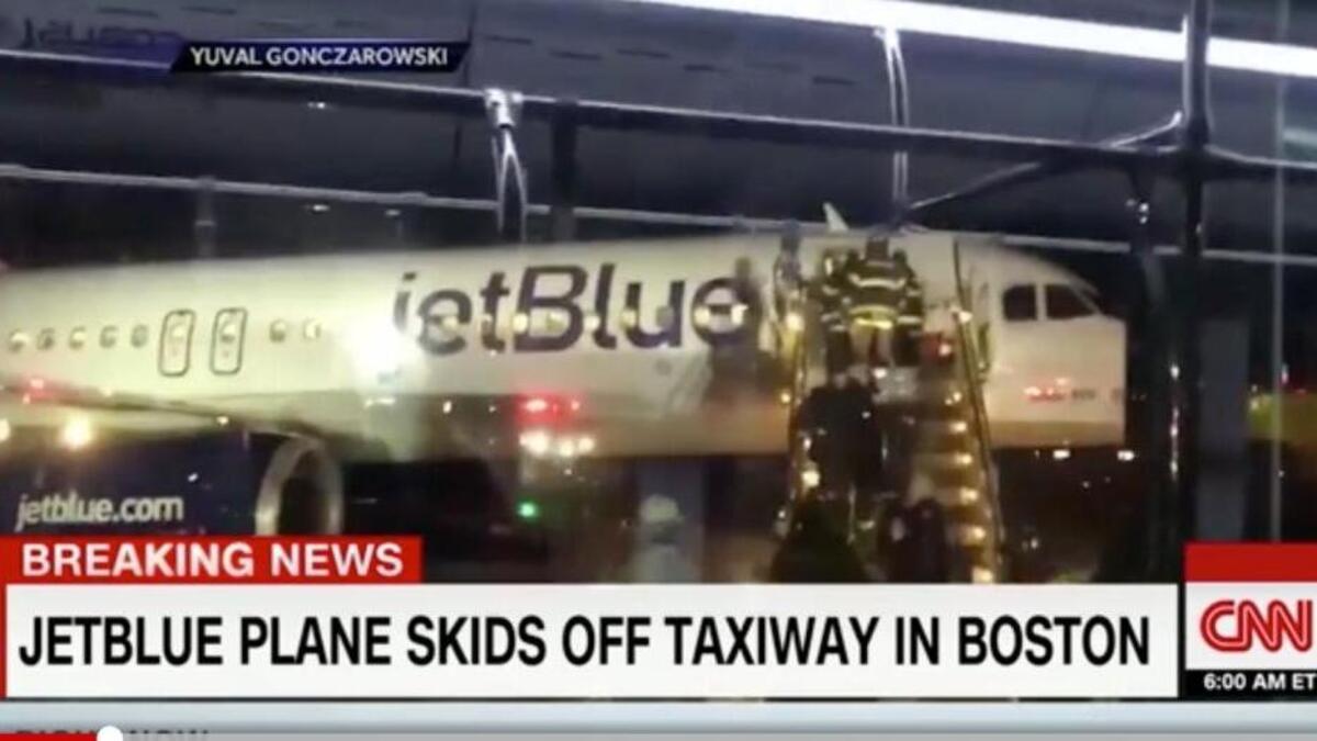 Video shows the plane stuck in a snow bank while firefighters help passengers off the plane after it slid off the runway at Logan Airport in Boston on Monday.