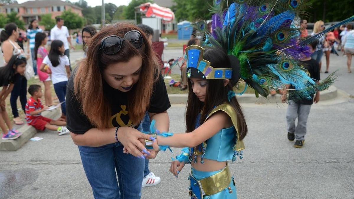 Ava Bello, left, of Bluffton, fixes one of the cuffs worn by her daughter Abril, 8, before the Miss Chiquitita contest during the first Festival Latino Cinco de Mayo on Sunday, May 1, 2016, at Bluffton Village in Bluffton. Abril wore clothing to represent the Aztec culture and Mexico in the contest.