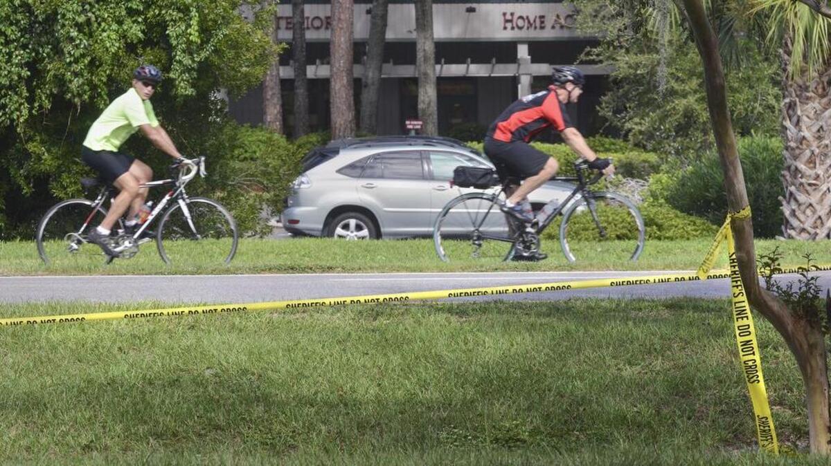 A pair of bicyclists pedal, on Sept. 19, 2016, past the scene of hit-and-run accident that killed a bicyclist on William Hilton Parkway. The accident occurred just south of the Queens Way intersection early Saturday morning and was still marked on Monday morning with crime scene tape. Matthew Proctor, 54, was identified as the victim. The vehicle that struck Proctor is described by South Carolina Highway Patrol as burgundy or maroon with damage on the driver’s side front bumper, hood and grill area, with possible windshield damage. The exact make and model of the car are unknown. Anyone with information can call the South Carolina Highway Patrol at 843-953-6010 or 1-800-768-1506.