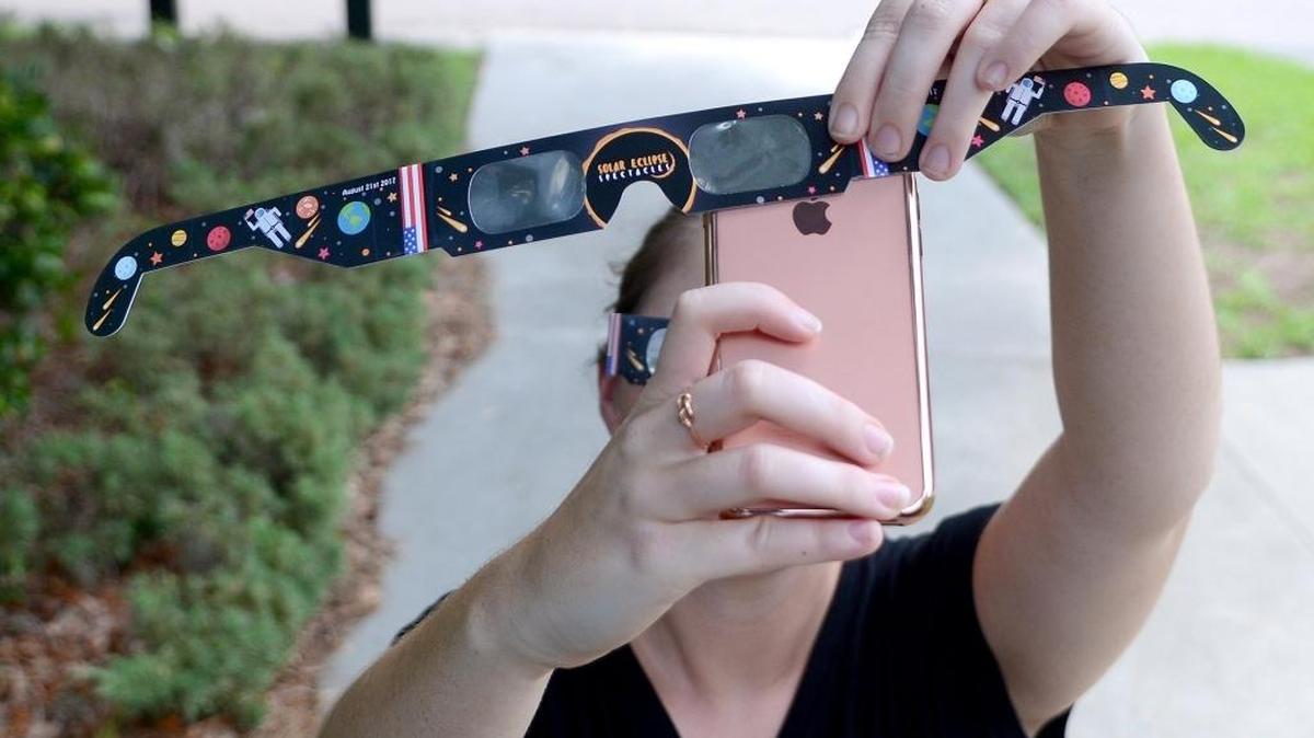 A woman holds a smartphone towards the sky while shielding the camera lens with a pair of glasses meant to protect your eyes during the eclipse during this photo illustration taken on Friday afternoon in Bluffton. To see a video on how to use your smartphone to photograph the eclipse go to www.islandpacket.com.