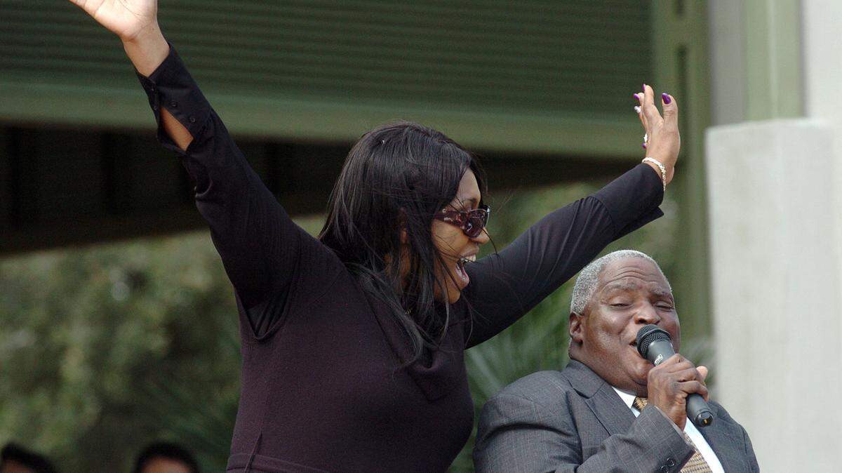 Scott Gibbs is joined by Jacqui Frazier Lyde for a song at the end of Wednesday's service at Henry C. Chambers Waterfront Park in downtown Beaufort. Frazier, who grew up on his family's 10-acre farm in the Laurel Bay area, died Nov. 7 at the age 67 after a brief fight with liver cancer.