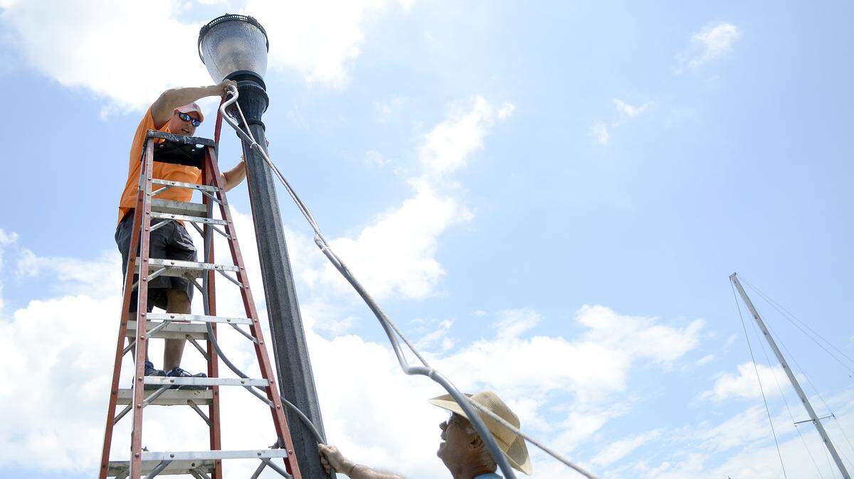 Jeremy Brown, left, of St. Helena Island talks with Kin Mack of Beaufort as they attach electrical wires to a light post July 15, 2014, in preparation for the arts and crafts fair that runs daily in front of the Beaufort Downtown Marina during the Beaufort Water Festival, which starts Friday. To get an interactive festival schedule for your smartphone or iPad, visit bit.ly/h2ofest-sked on your device's web browser and save it to your home screen.