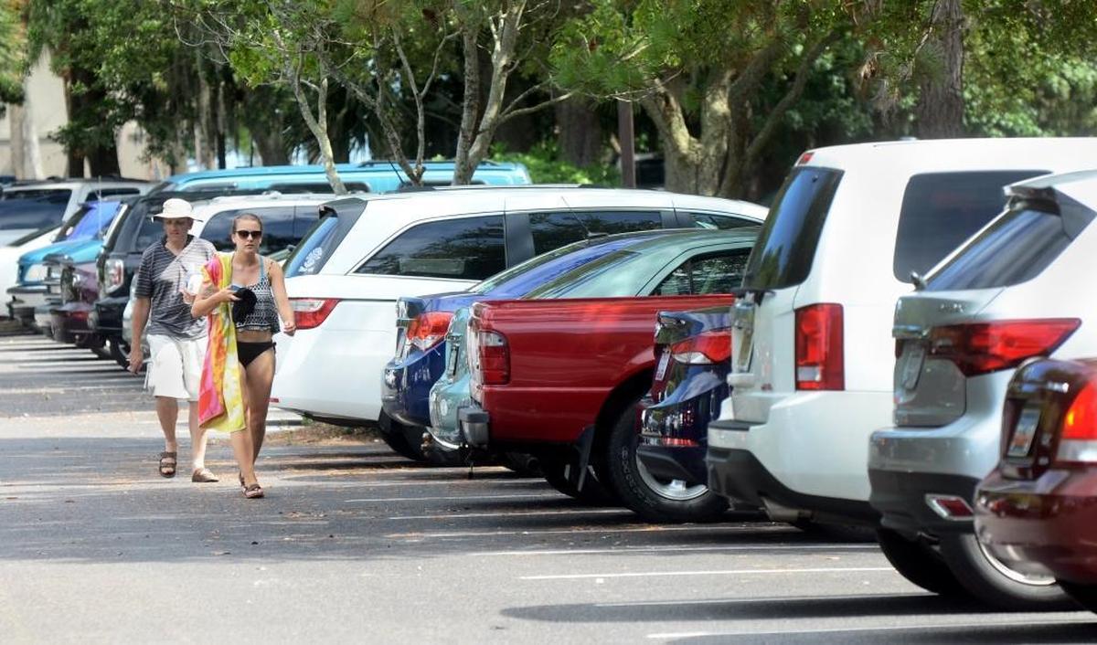 In this file photo, beachgoers walk through the crowded Coligny Beach public parking lot.