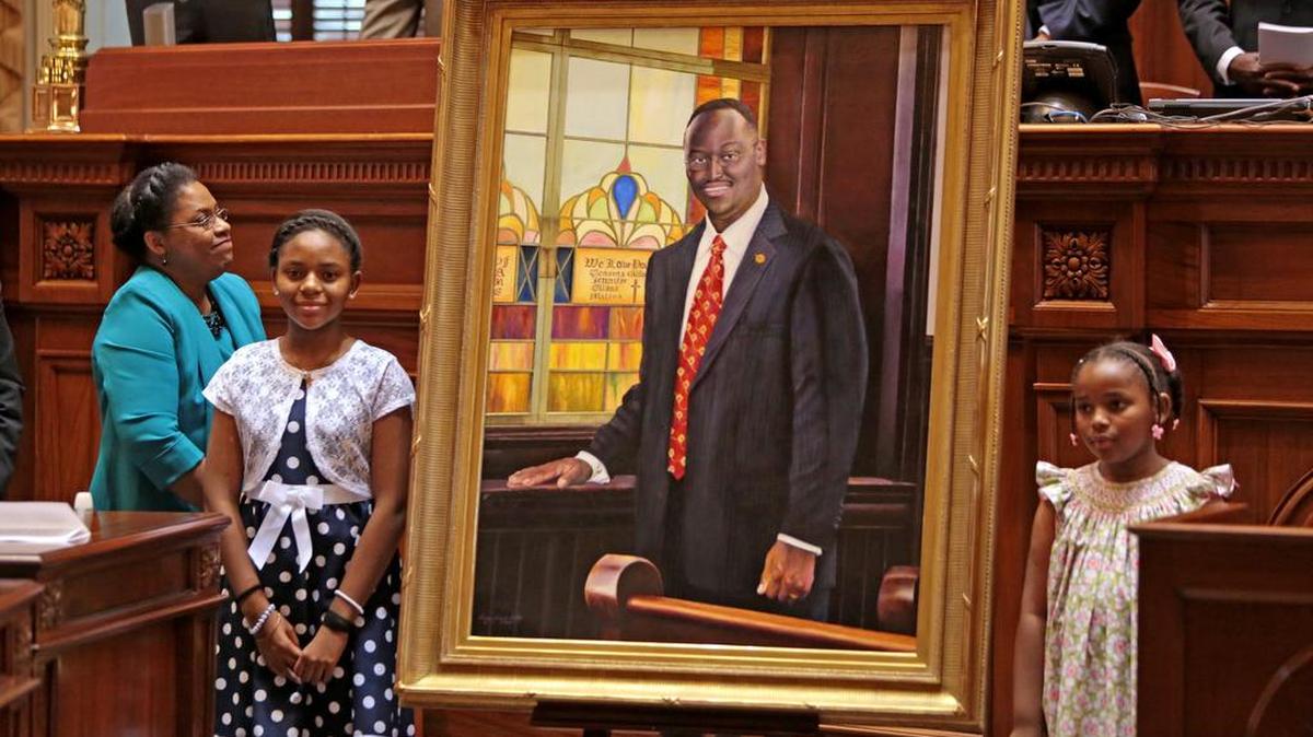 Clementa Pinckney’s wife Jennifer and daughters Eliana and Malana stand next to his portrait after unveiling it during a ceremony inside the Senate chambers of the State House on May 25, 2016.