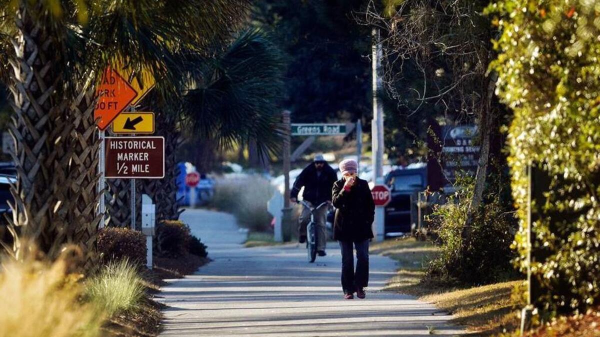 A man braves the freezing cold on bike as a woman covers her face while walking along Mathews Drive on Hilton Head Island early on January 8, 2015.