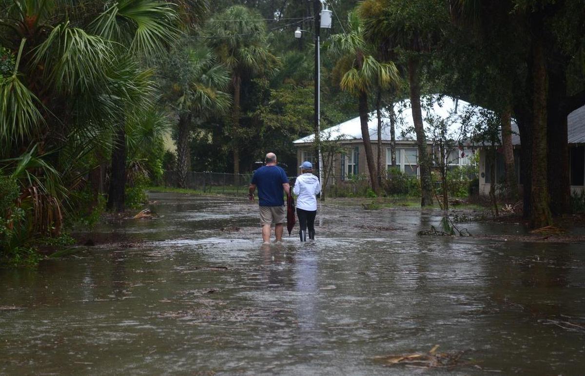 FILE: A couple walks along a road near Alljoy Landing on Sept. 11, 2017 in Bluffton flooded by a combination of an unusually high tide and storm surge from Tropical Storm Irma.