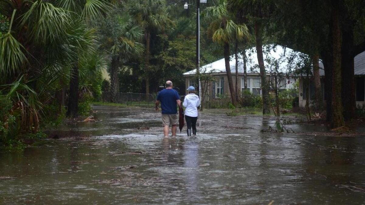 FILE: A couple walks along a road near Alljoy Landing on Sept. 11, 2017 in Bluffton flooded by a combination of an unusually high tide and storm surge from Tropical Storm Irma.