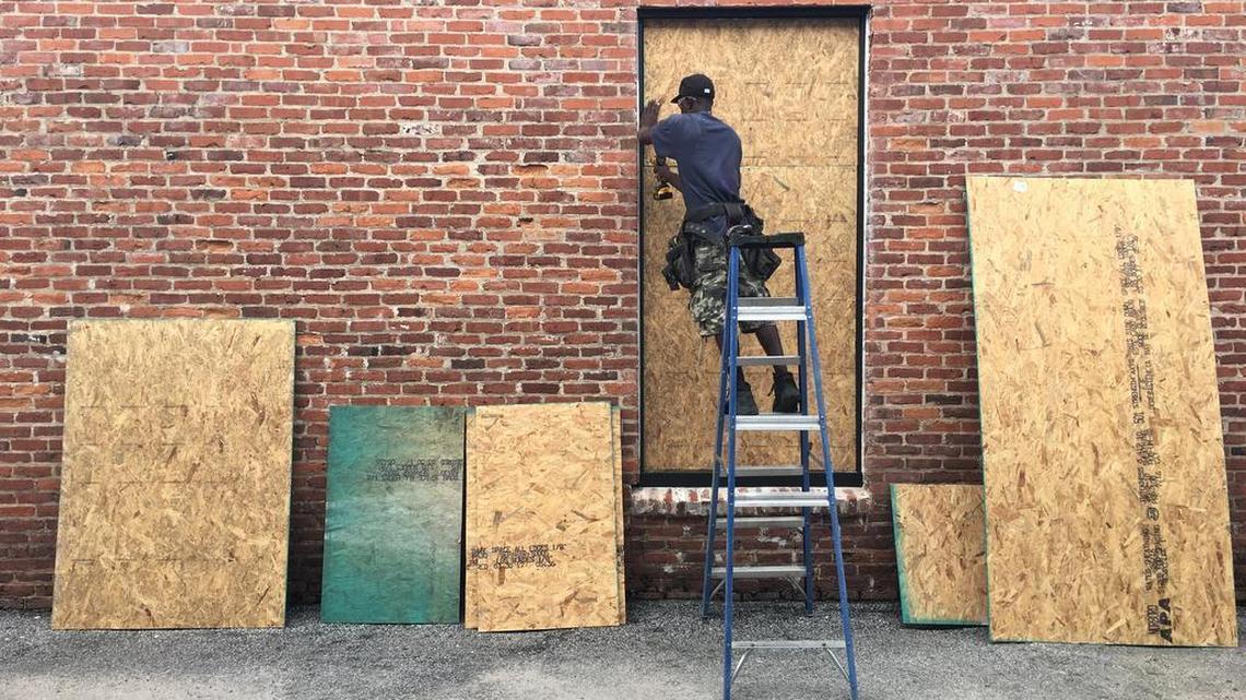 Chris Williams, a carpenter with Beaufort Design Build, secures plywood to one of the windows of Cook on Bay, on Thursday morning in Beaufort. The company is boarding up several of the business in Downtown Beaufort in preparation for Hurricane Irma.