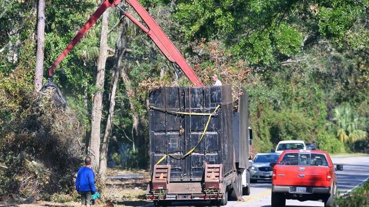 A truck with tandem trailers and a built-in crane collects Hurricane Matthew debris.