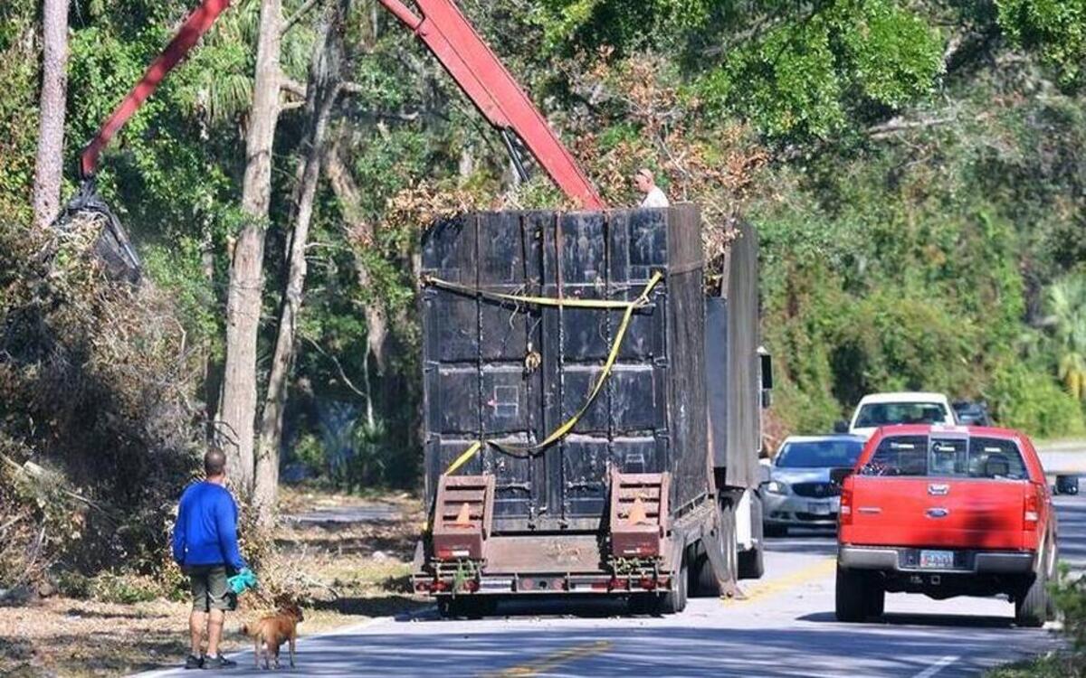 A truck with tandem trailers and a built-in crane collects Hurricane Matthew debris.