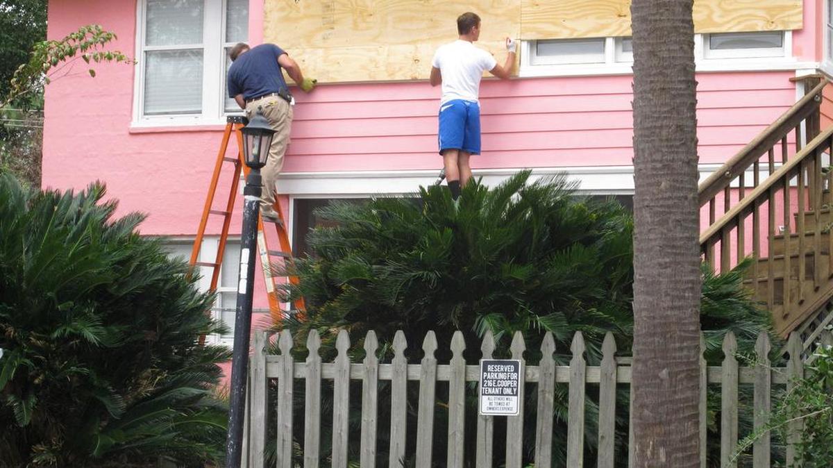 Workers hammer plywood over the windows of a home in Folly Beach. S.C., on Oct. 5, 2016.