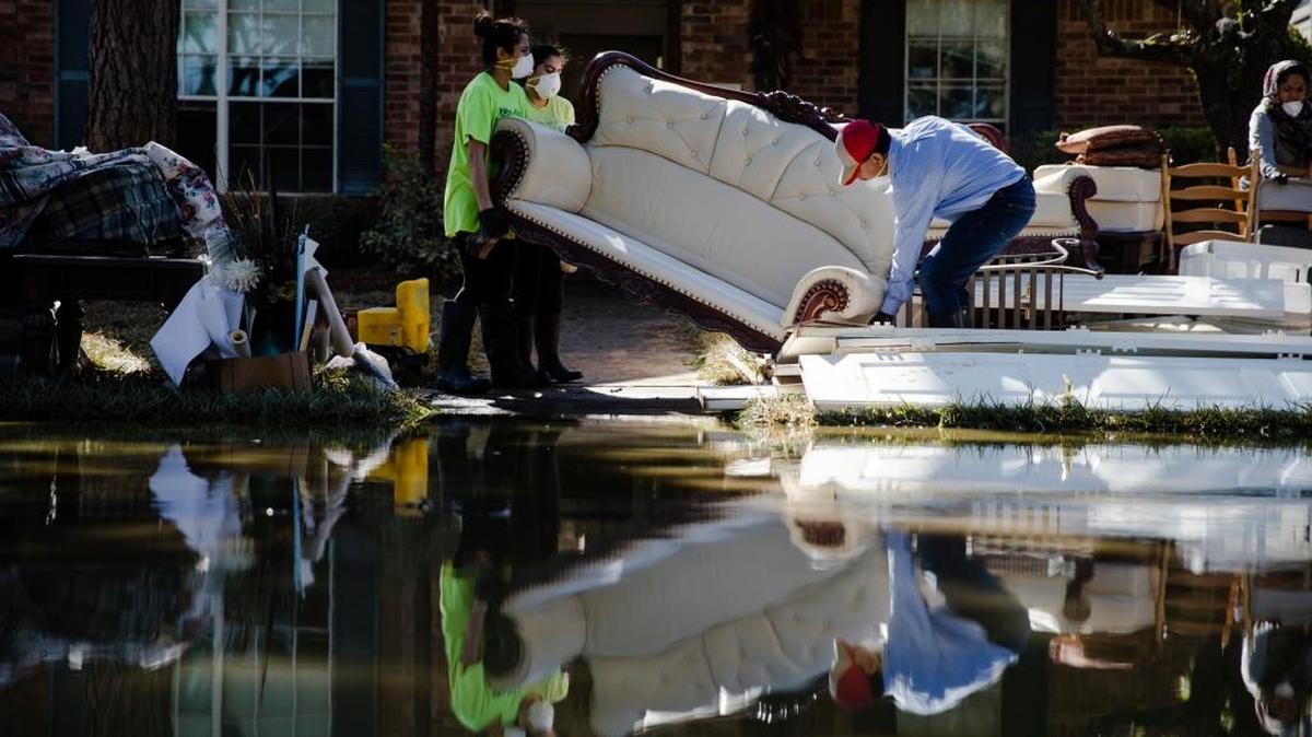 Homeowner Sohail Soomro, center right, accompanied by his family dumps flood damaged furniture on his front yard in the aftermath of Hurricane Harvey on Thursday, Sept. 7, 2017, at the Canyon Gate community in Katy, Texas.