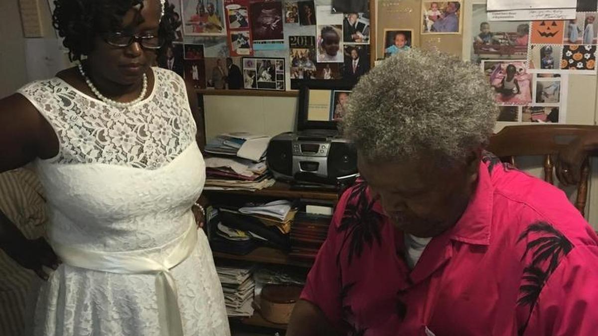 Terry Grant watches as the Rev. Ben Williams signs her marriage license on the day he married Grant and Christopher Robinson at his home on June 27, 2016.