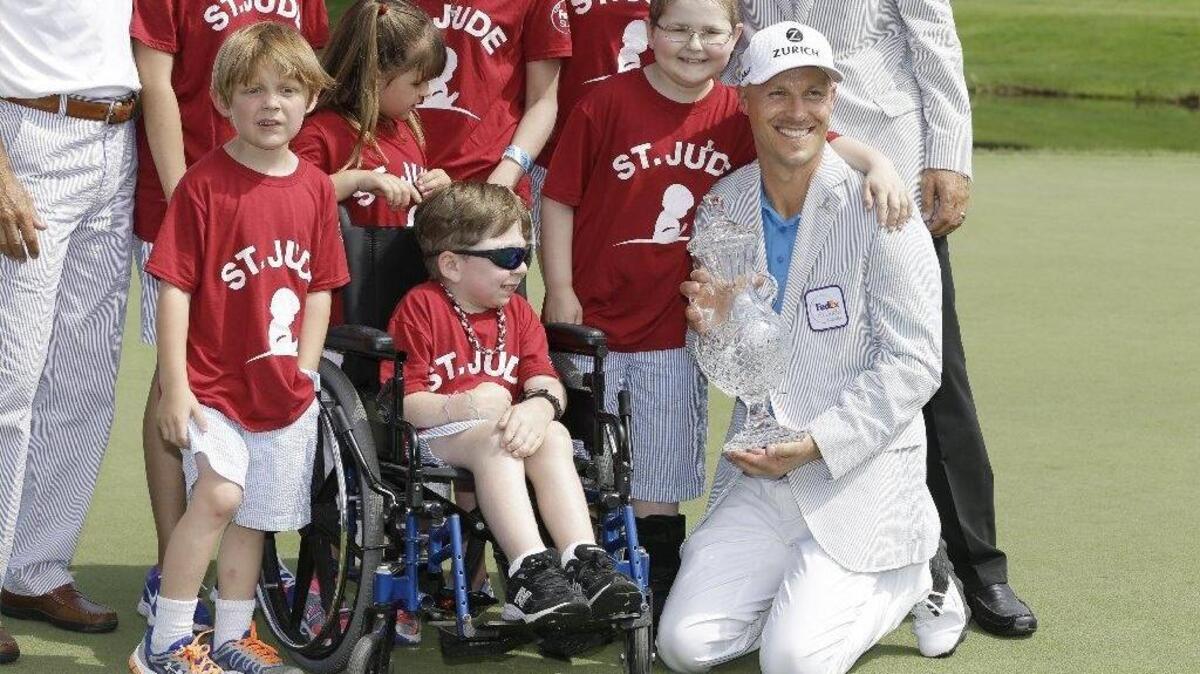 Ben Crane poses with his trophy and patients of St. Jude Children’s Research Hospital after winning the St. Jude Classic golf tournament Sunday, June 8, 2014, in Memphis, Tenn. Crane won the tournament with a score of 10-under 270.