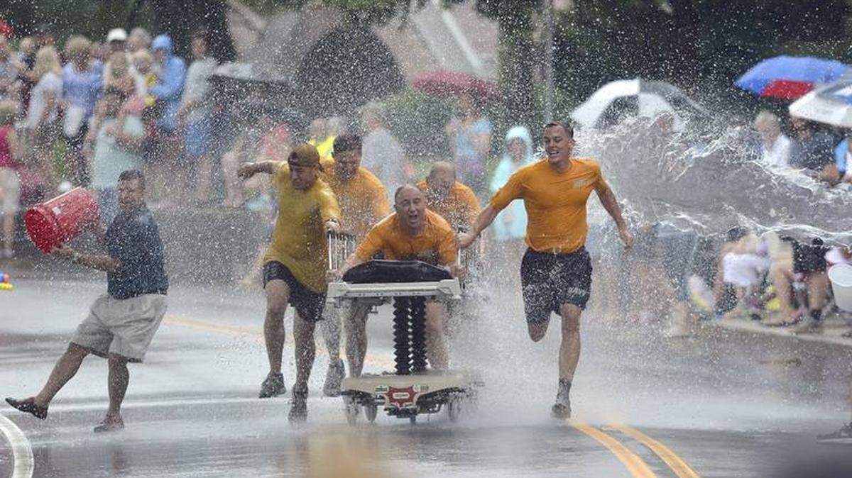 The Lowcountry Seabees team pulls a bed through a wall of water being thrown on them during a Bed Race in a past Beaufort Water Festival on Bay Street in downtown Beaufort.