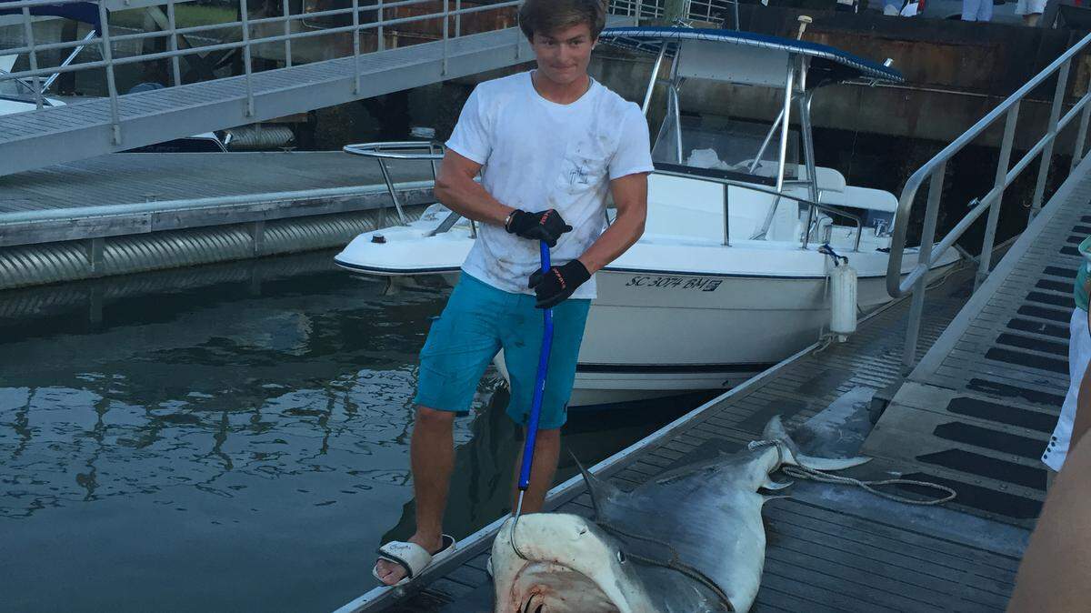 Hilton Head Island's Ryan Hiers, 19, stands on the dock at Hilton Head Boathouse on Sunday, Sept. 20, beside a 9-foot tiger shark he and his father caught about 8 miles off shore.