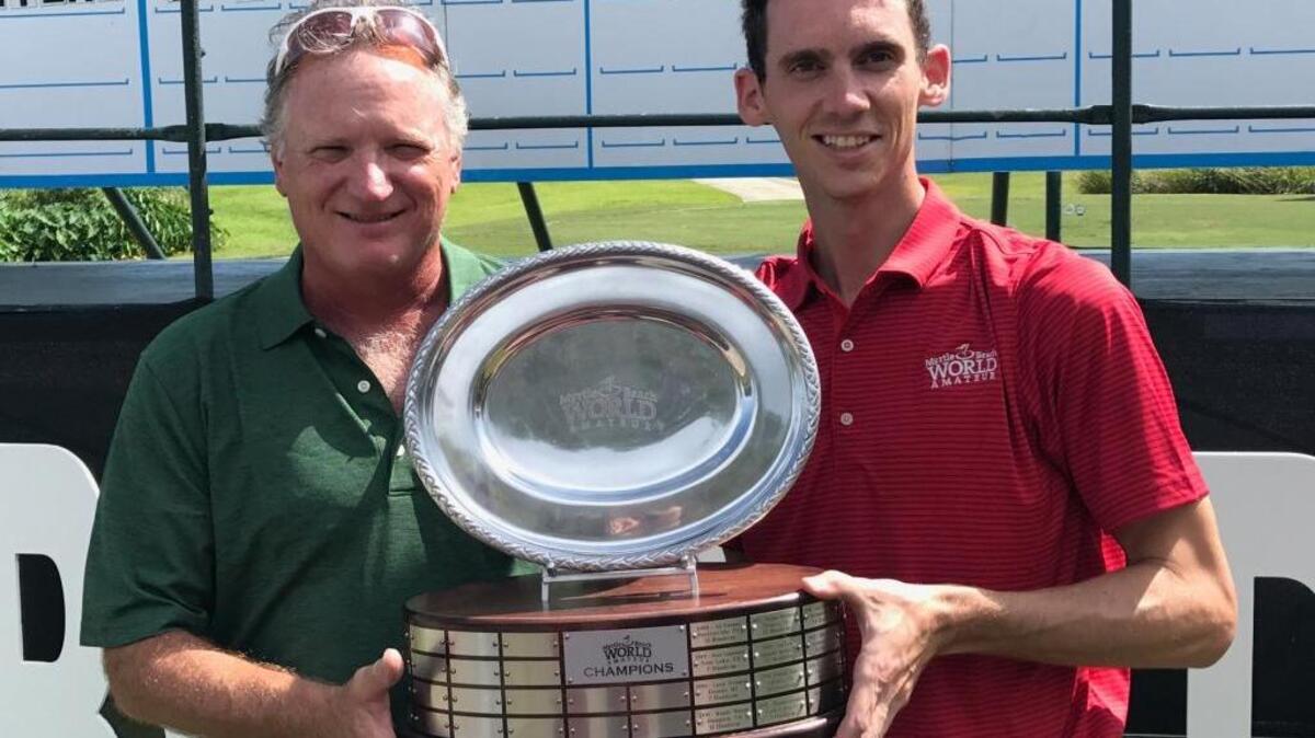 Curtis Henley of Poquoson, Va., left, accepts the trophy from tournament coordinator Scott Tomasello after winning the 34th World Amateur Handicap Championship at Barefoot Resort’s Dye Club on Friday.