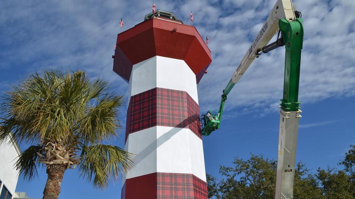 Workers apply adhesive vinyl with a Heritage plaid pattern to the Harbour Town Lighthouse on Tuesday. The lighthouse will be white and plaid striped in honor of the 50th anniversary of the RBC Heritage Presented by Boeing golf tournament, and will remain that way until the conclusion of this year's tournament, on April 19.