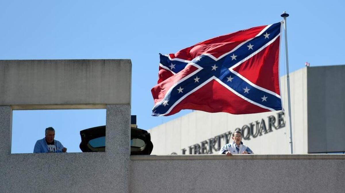 Basketball fans look out as a Confederate flag flies from a parking deck outside the arena on March 19 before a second-round game of the NCAA men’s college basketball tournament in Greenville.
